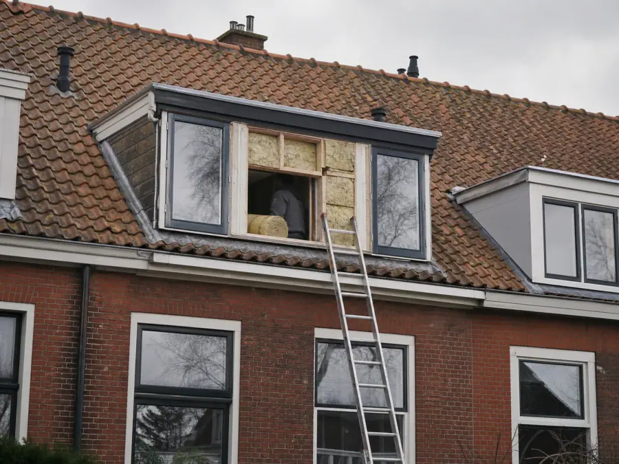Groningse jaren-20 bouwblok met een ladder tegen de gevel en werk aan de dakkapel