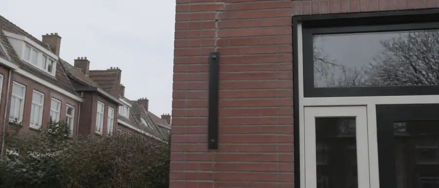 Bakstenen gevel met een herstelde scheur en een ingetogen stalen steunbeugel