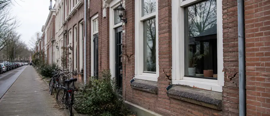 Woonstraat in de stad Groningen met bakstenen gevels, hoge ramen en fietsen langs de stoeprand