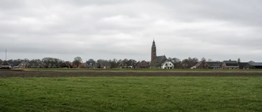 Gronings buitengebied met een lintdorp van bakstenen huizen en een kerktoren aan de horizon